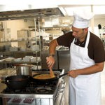A professional chef in a white uniform cooking in a commercial kitchen, representing the commercial pest control and sanitation services provided by Omaha Pest Control in Nebraska.