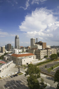 High-angle view of the Council Bluffs, Iowa skyline featuring the Historic Pottawattamie County Courthouse and modern office buildings under a cloudy blue sky.